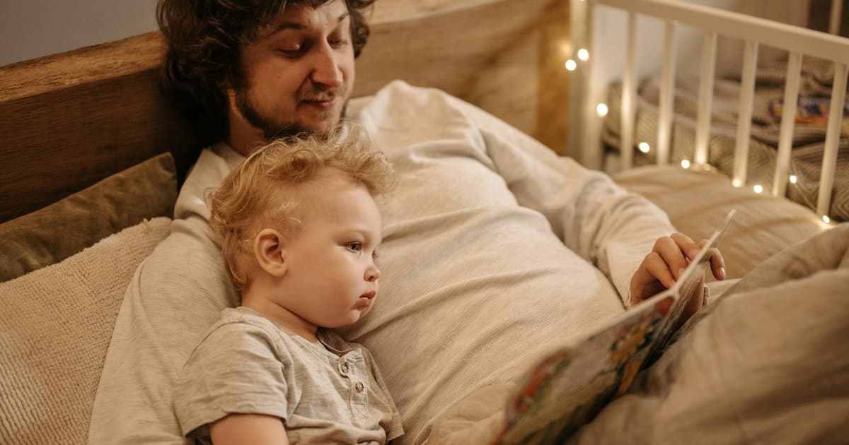 Father and child reading a book together at bedtime, illustrating traditional storytelling for kids.