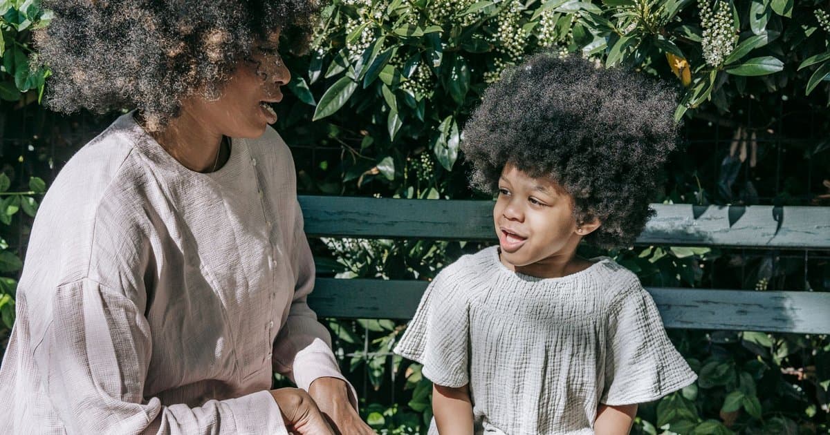 A mother and child sit on a bench, discussing the emotional aspects of starting school.