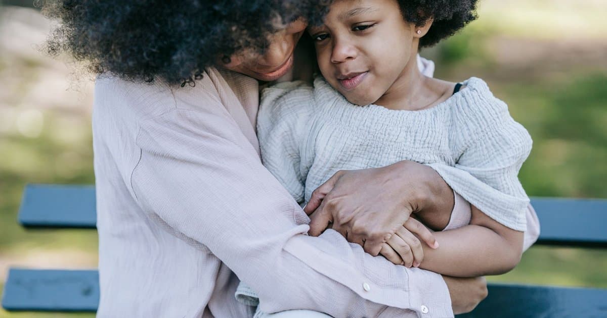 Mother and daughter hugging on a park bench, illustrating emotional support for anxious children.