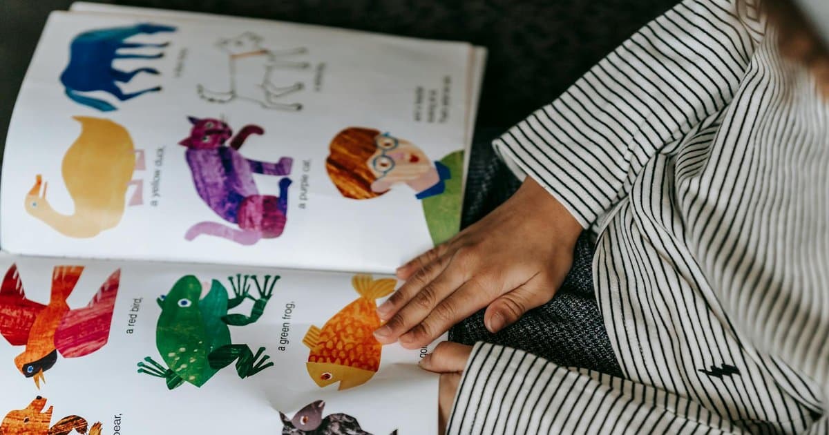 Child reading a colorful picture book about animals, representing stories that help build confidence.