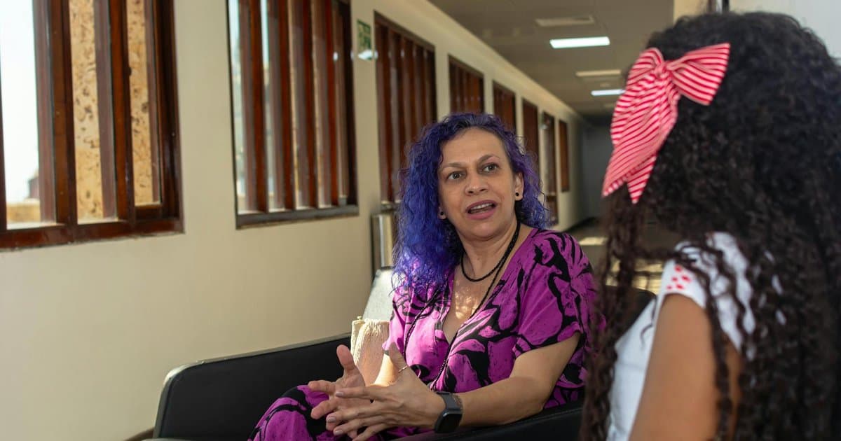 A counselor with dyed hair talks with a student in a school hallway, representing meaningful counselor appreciation gifts.