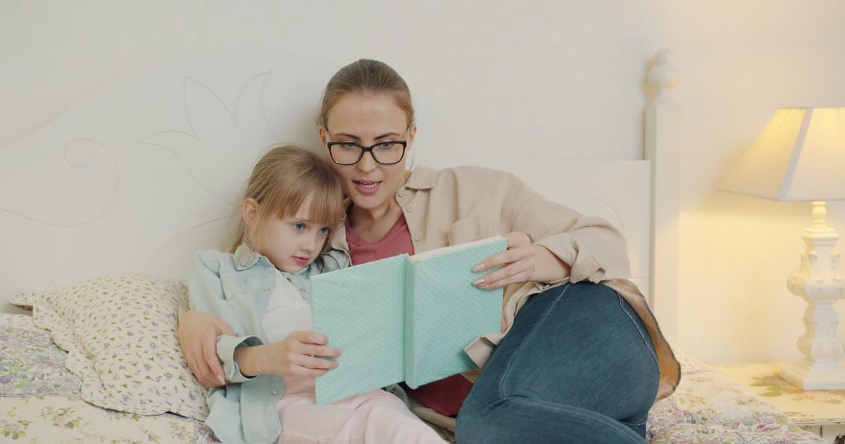 Mother reading a bedtime story to her daughter in bed, illustrating the importance of personalized stories for children's sleep.