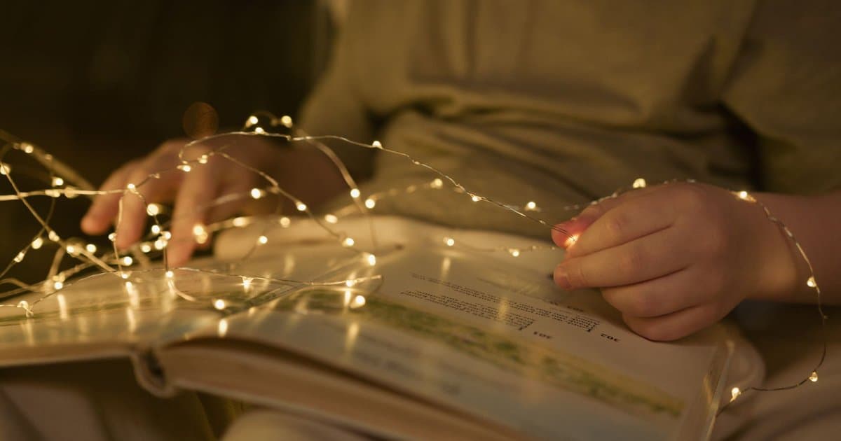 Child reading a personalized book under string lights, illustrating how custom stories engage young readers.
