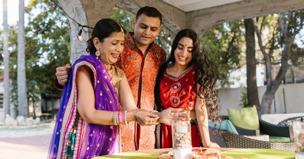 Family in traditional clothing lighting candles outdoors during Diwali celebration.