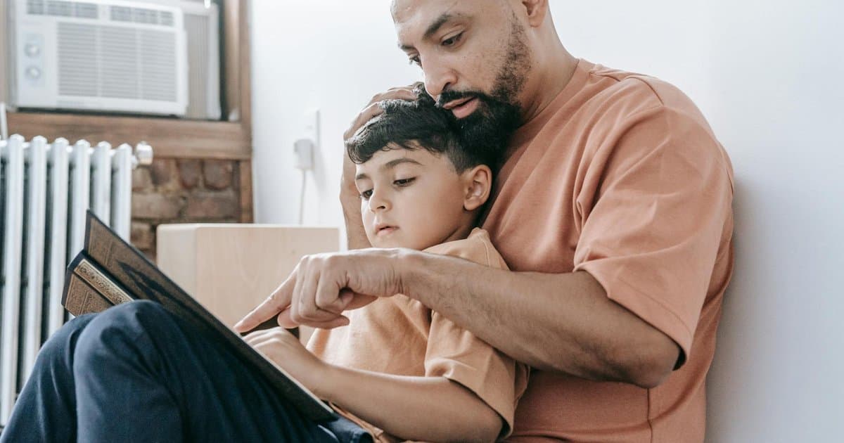 Father reading a book to his son indoors, illustrating parent-child reading engagement.