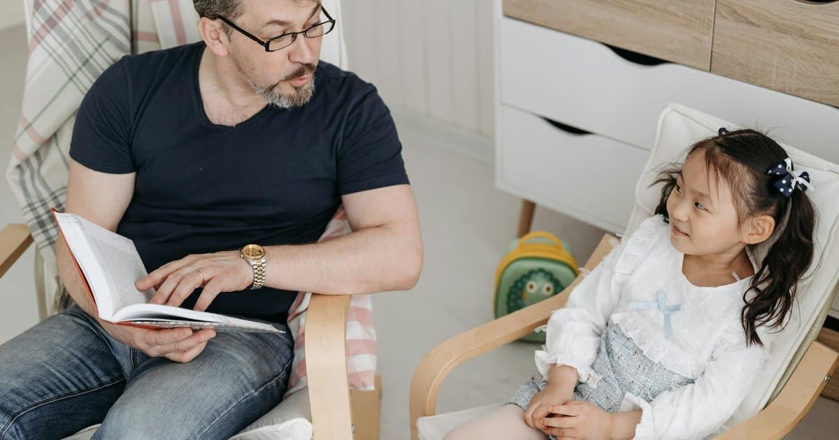 Father reading a book to his daughter, illustrating how stories can support potty training.