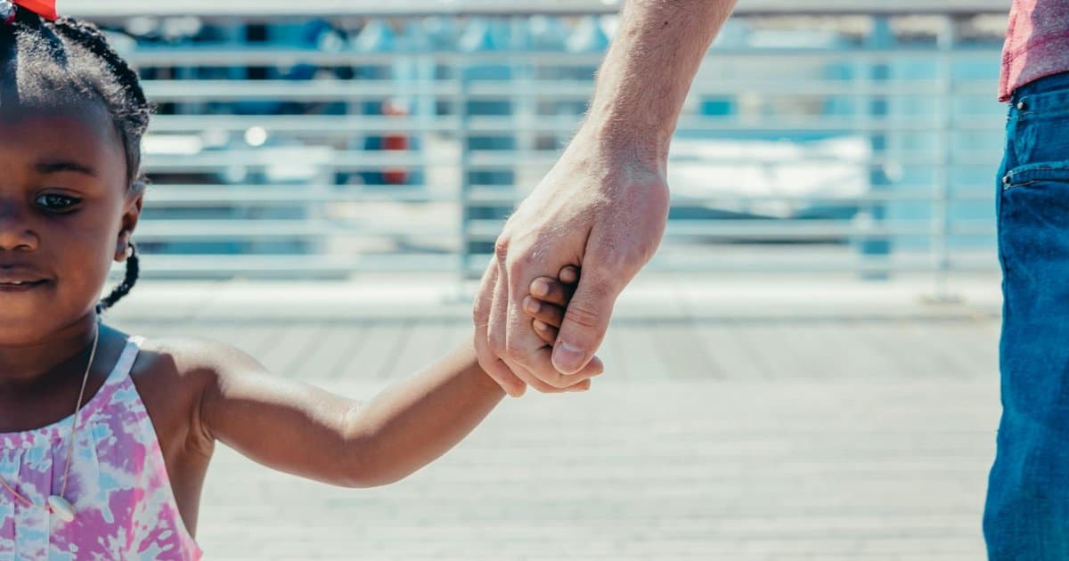 Father and young daughter holding hands outdoors, representing affordable gift ideas for teachers.