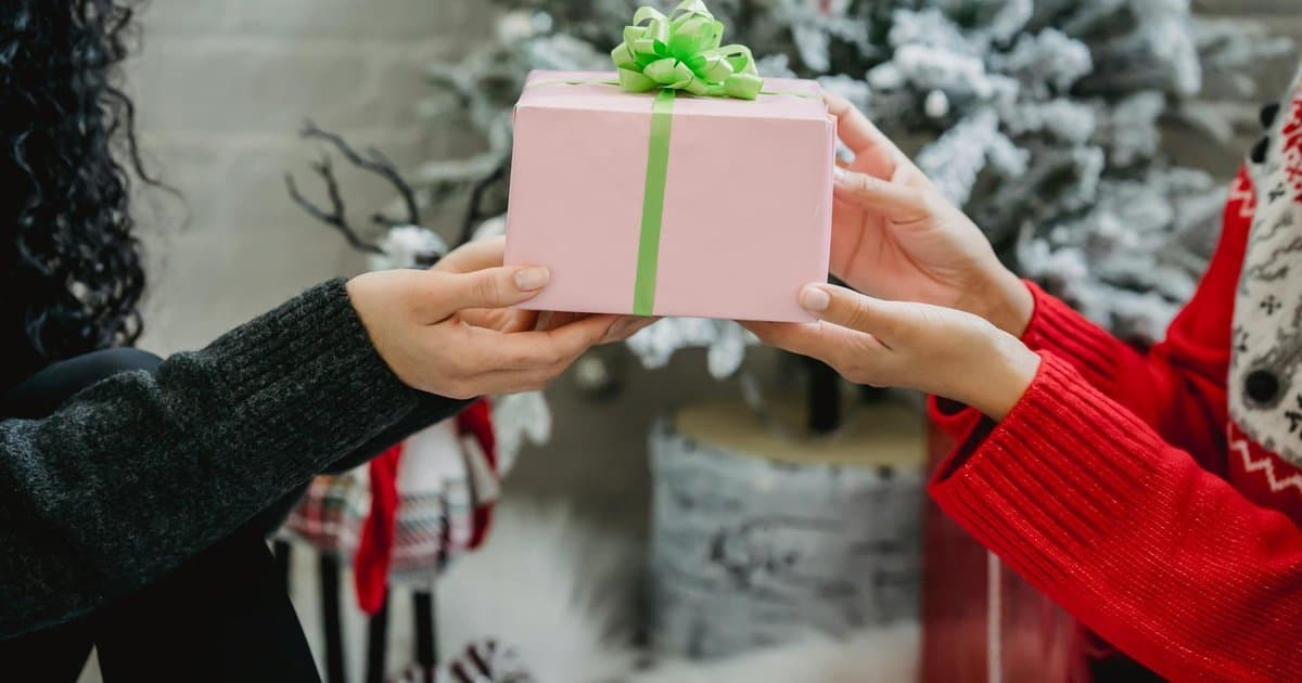 Woman receives a wrapped gift from a child, representing teacher appreciation gifts from students
