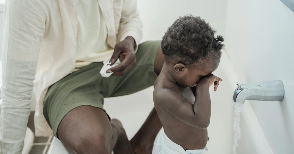 Father helping toddler with bathroom routine, representing potty training support for young children.