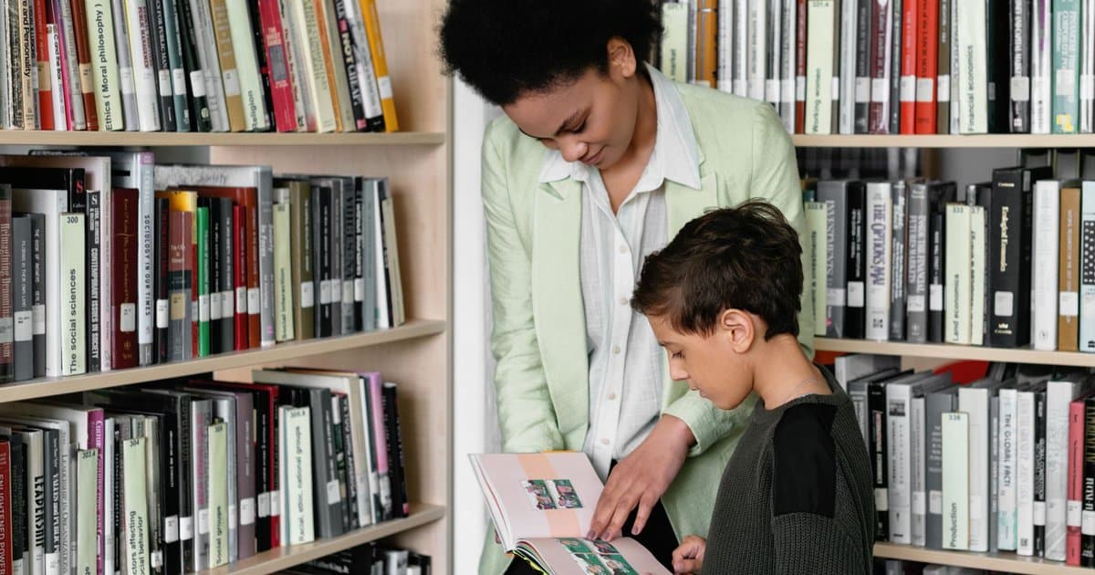 Adult and child reading a book together in a library to build early literacy skills.