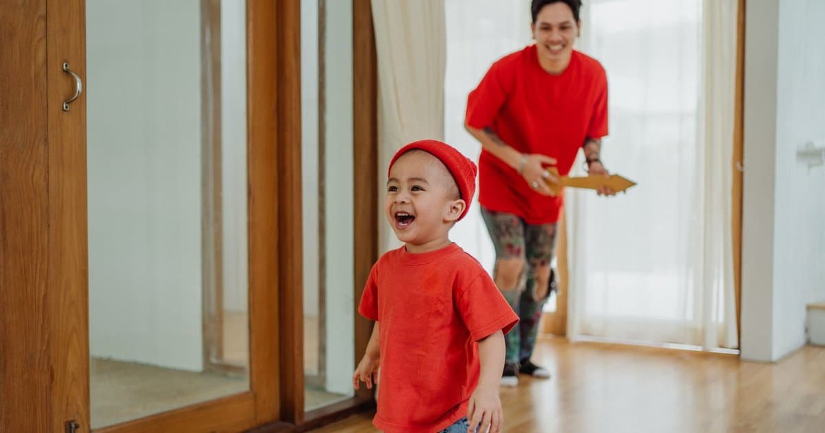 Father and toddler playing with a toy guitar together in a bright home, illustrating meaningful gift choices for young children.