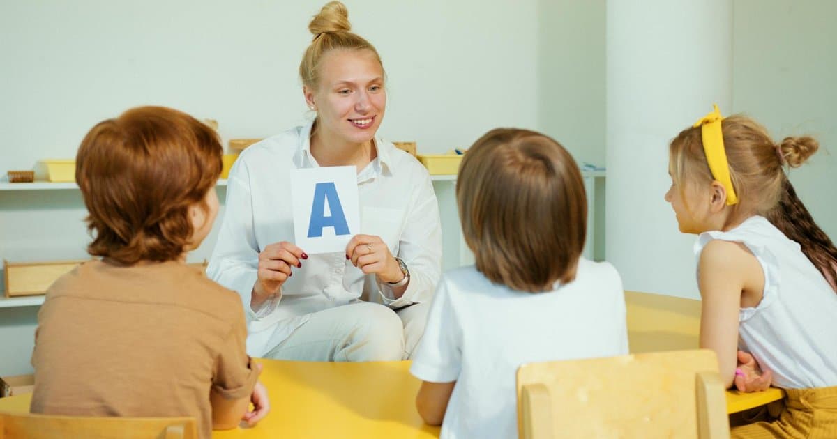 Teacher holding a letter card with preschool students in classroom, illustrating meaningful engagement with children.