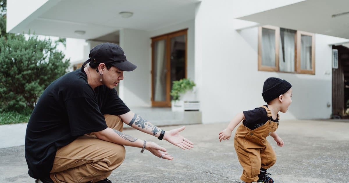 Father playing with toddler son in front yard, demonstrating family connection for building emotional wellness.