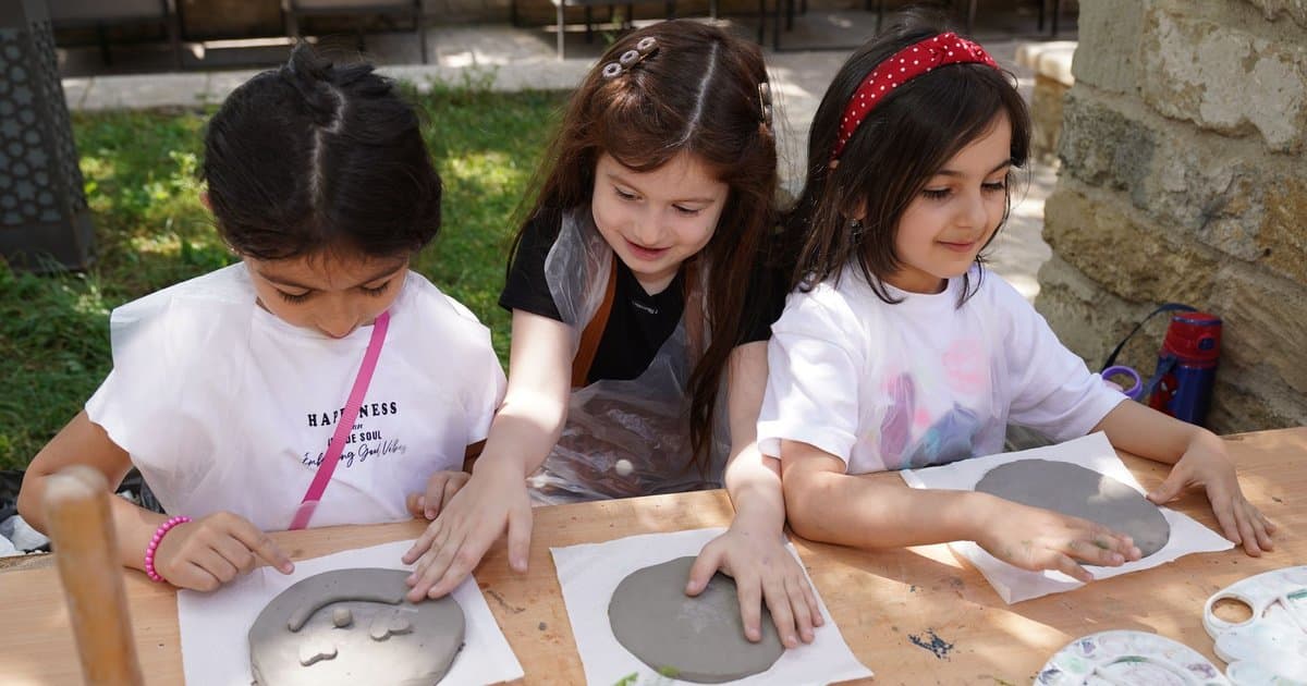 Children crafting with clay outdoors, demonstrating a handmade gift-making activity for teachers.