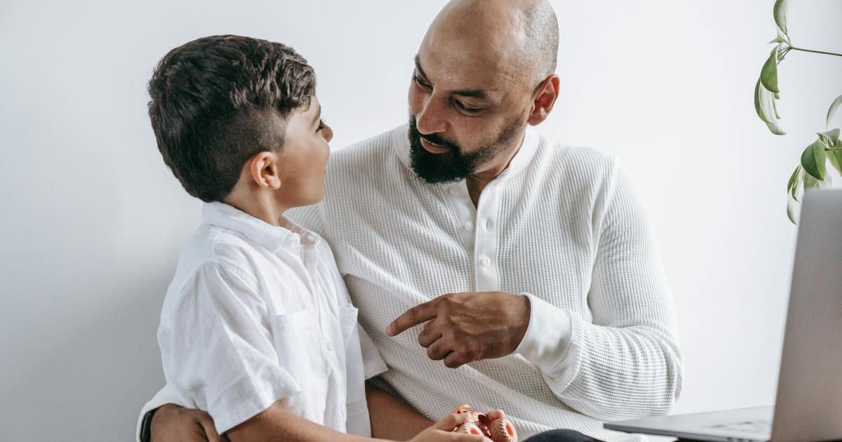 Father and son talking at home, illustrating supportive communication for building children's confidence.