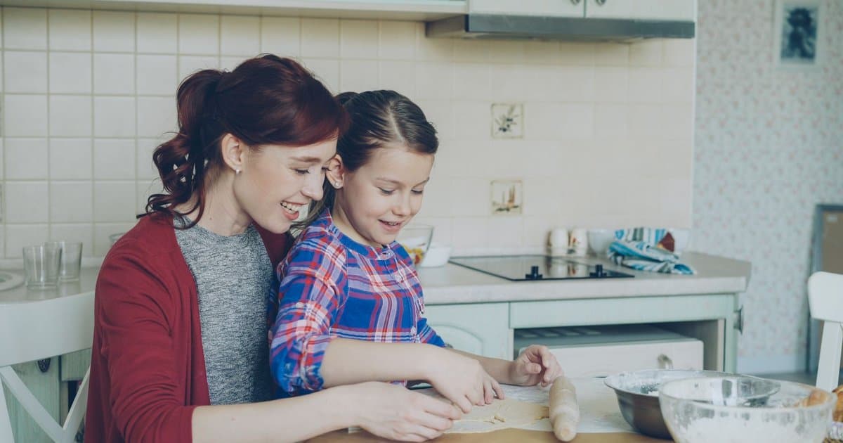 A mother and daughter bake together in a kitchen, representing bonding during blended family transitions.