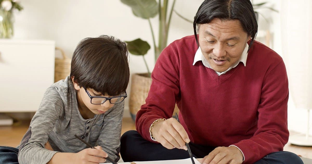 Father and son practice calligraphy together, illustrating meaningful written communication between parent and child.