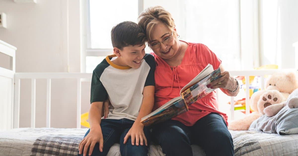 Grandmother and grandson reading a book together, representing intergenerational storytelling between grandparents and children.