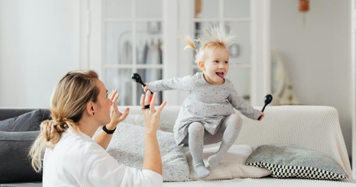 Mother and toddler playing together on a sofa, showing meaningful interaction over material gifts.