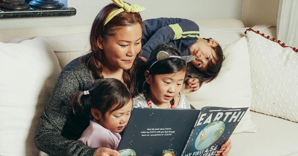 A mother and children read together on a sofa, illustrating a Mother's Day book gift idea for preschoolers.