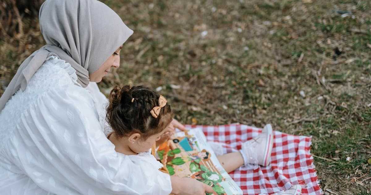 Mother and daughter reading together on a picnic blanket, illustrating family bonding moments to share as Christmas stories.