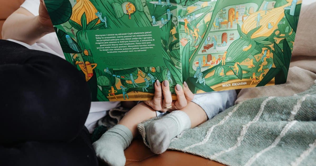 A mother and child reading a colorful book together on a sofa, illustrating how personalized sports books engage young readers.