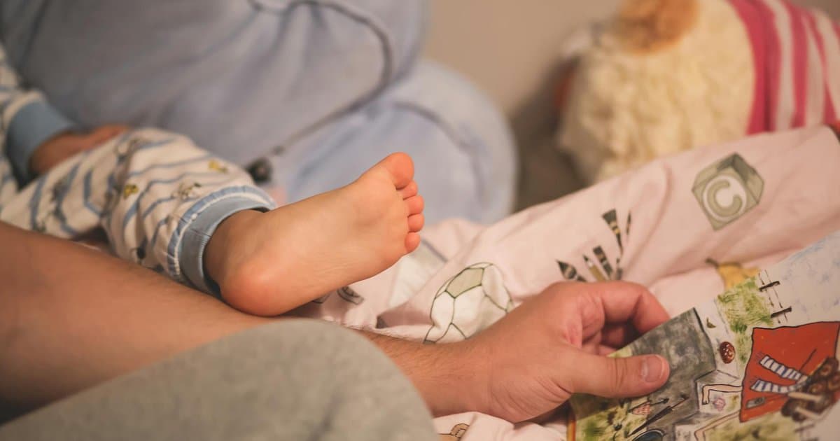 Parent and child reading together at bedtime, illustrating storytelling's role in sleep routines.