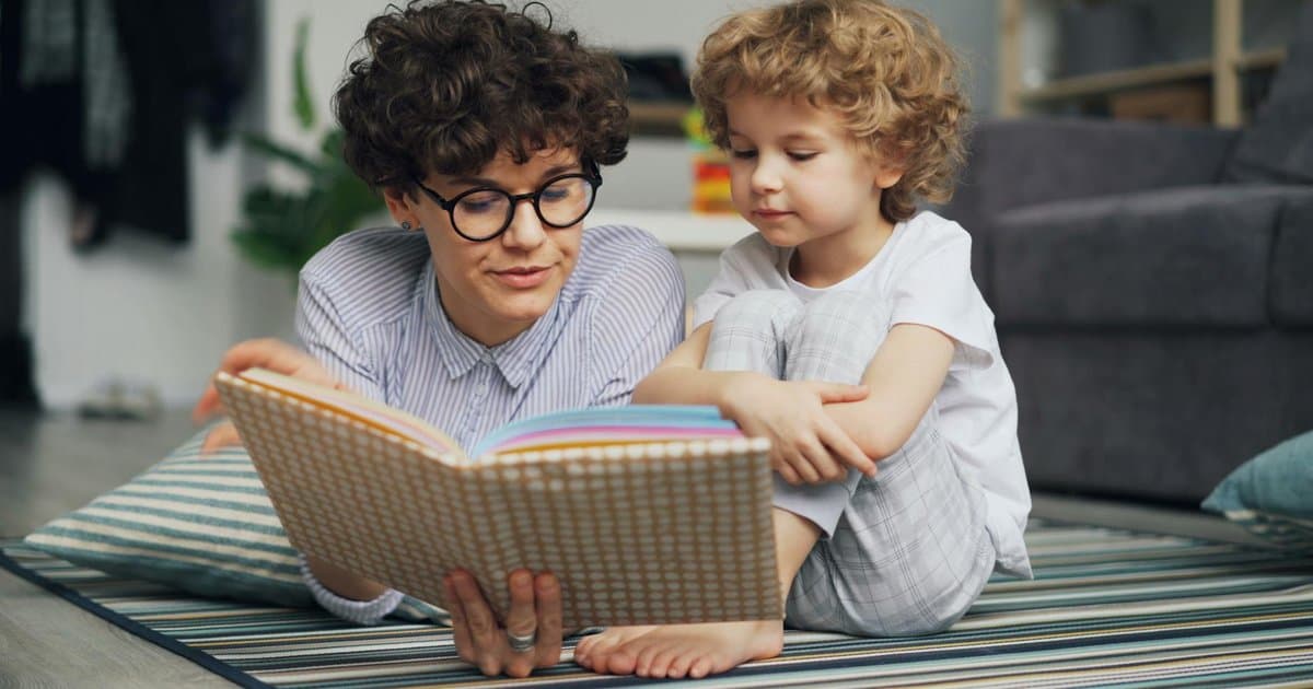 Mother and young son reading a book together on carpet, illustrating the impact of personalized books on children.