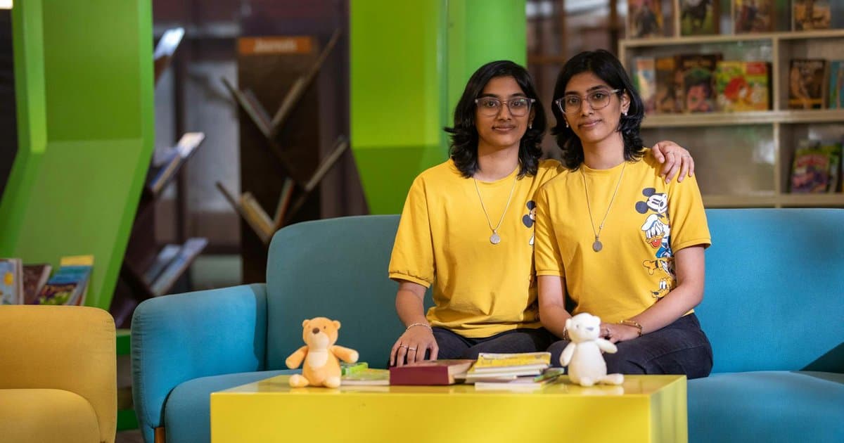 Twin girls reading together on a couch, illustrating why personalized books help each child feel individually recognized.
