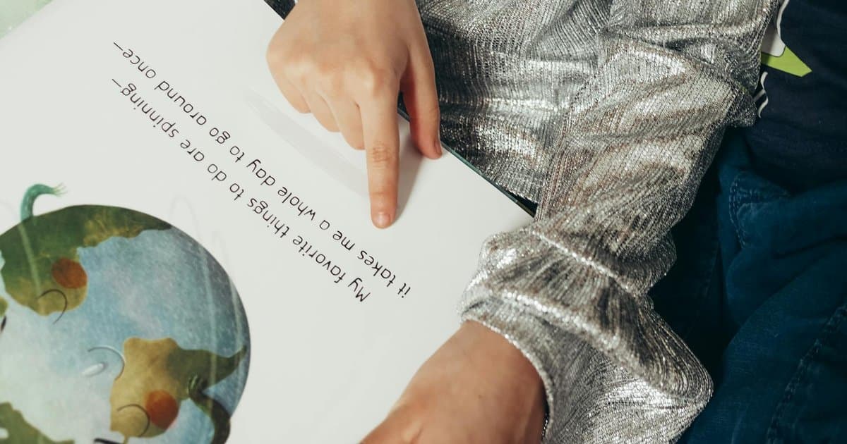 Child pointing to text in an illustrated book, exploring how personalization impacts reading engagement.