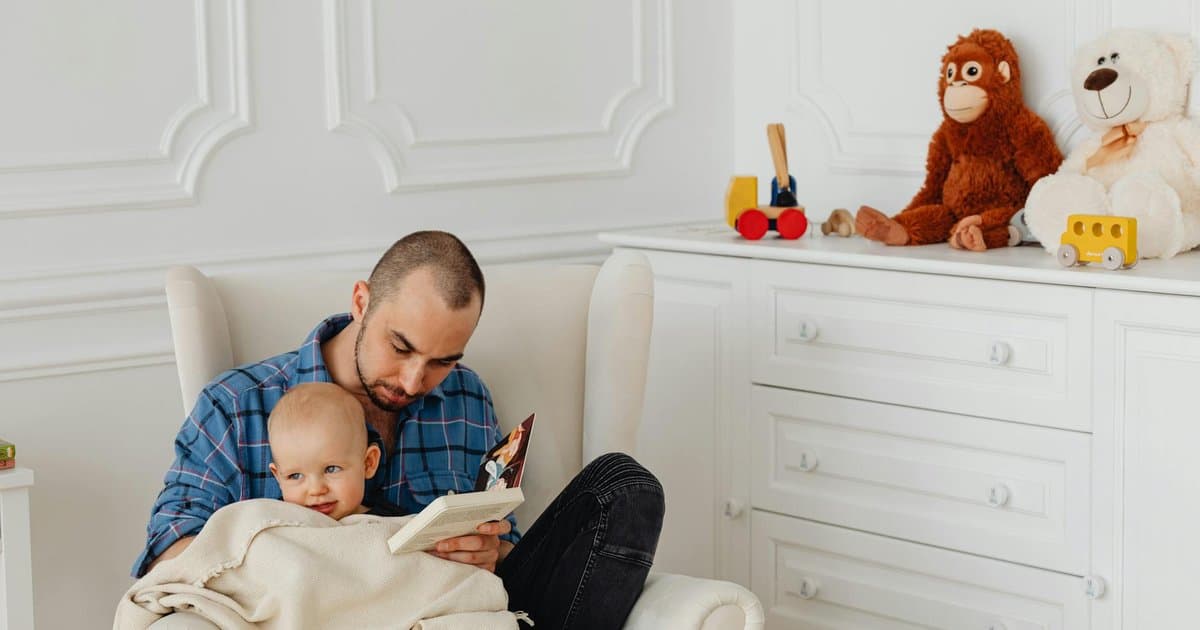 Father and baby reading together in a nursery, showing the bond books can create between parent and child.