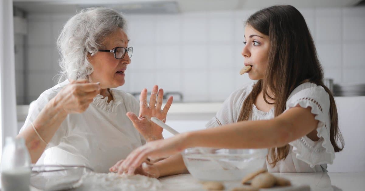 Grandmother and granddaughter baking together in the kitchen, sharing a bonding moment through a personalized gift activity.
