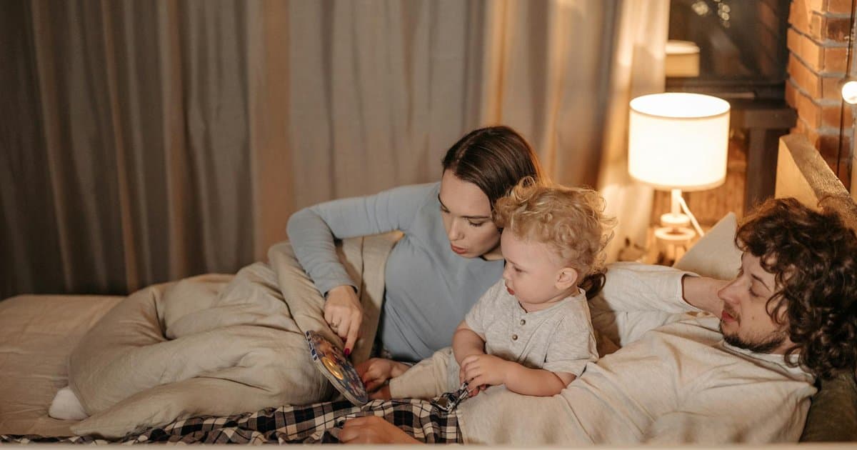 Parents reading a bedtime story to their child in bed, illustrating how personalized books may influence sleep habits.