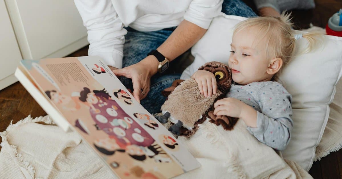 Parent and child reading a storybook together with a toy owl, illustrating the bonding power of personalized books.