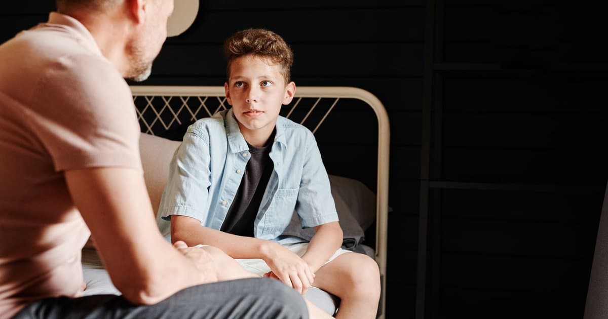 Father and son talking indoors, illustrating parent-child communication about attending a wedding.