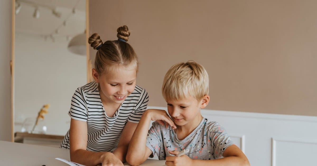Two children study together at a table with a book, representing educational activities for the Islamic holy month.