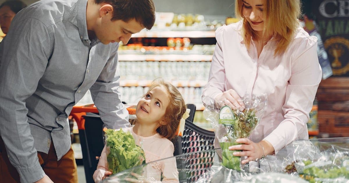 A family shops for produce together in a supermarket, demonstrating sensory-friendly grocery shopping strategies.