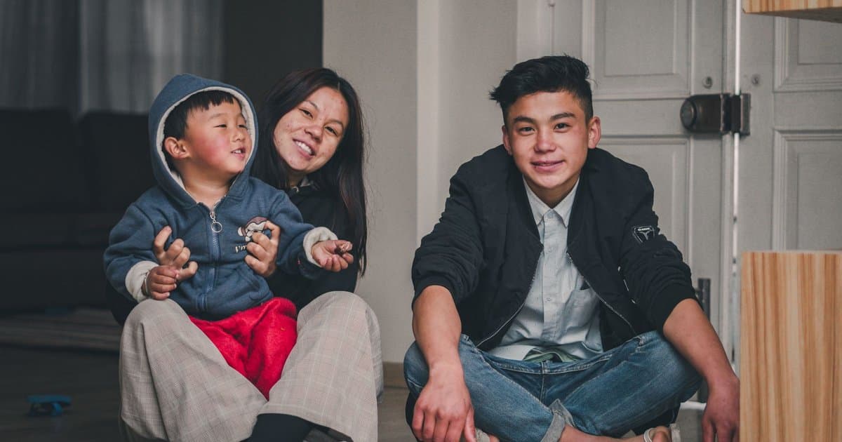 A family sits together indoors, modeling the bonding and support children need when preparing for a sibling's NICU stay.