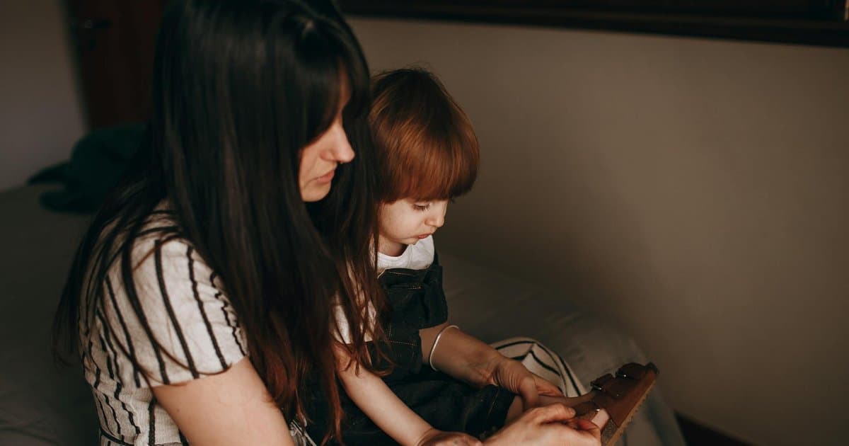 A mother and young daughter sit together indoors while discussing social skills and friendship-building strategies.