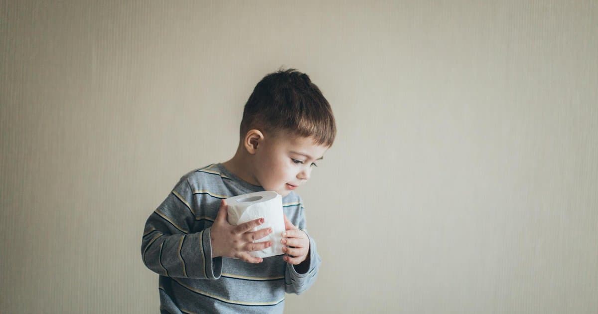Young boy holding toilet paper, illustrating bathroom readiness for potty training preparation.