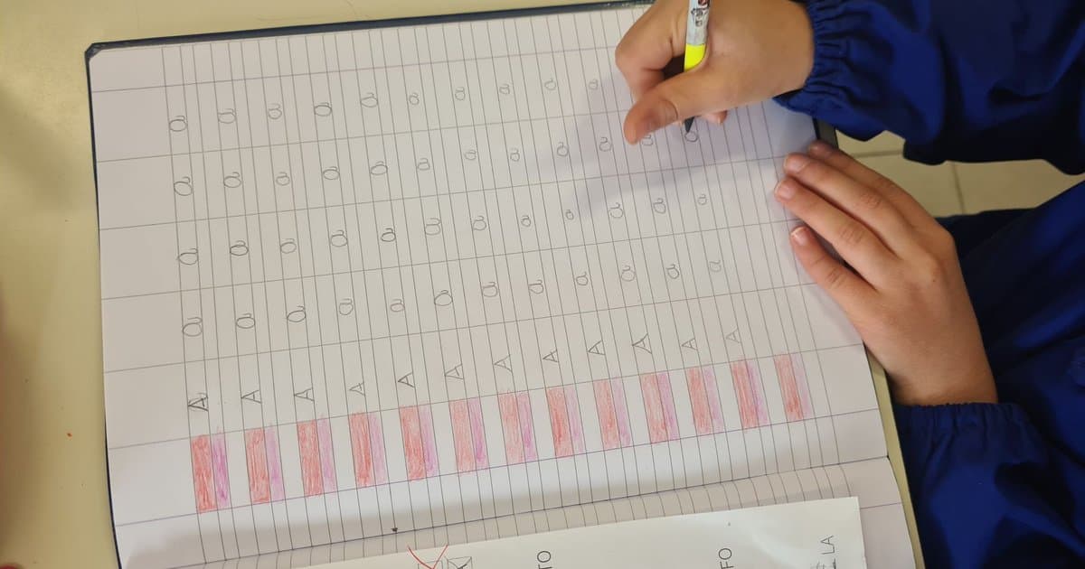 Child writing in a notebook, practicing letter writing to share with grandparents.