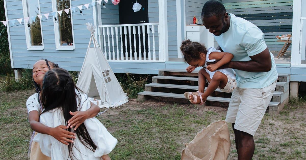 Two adults and children playing outdoors together, representing diverse family structures.