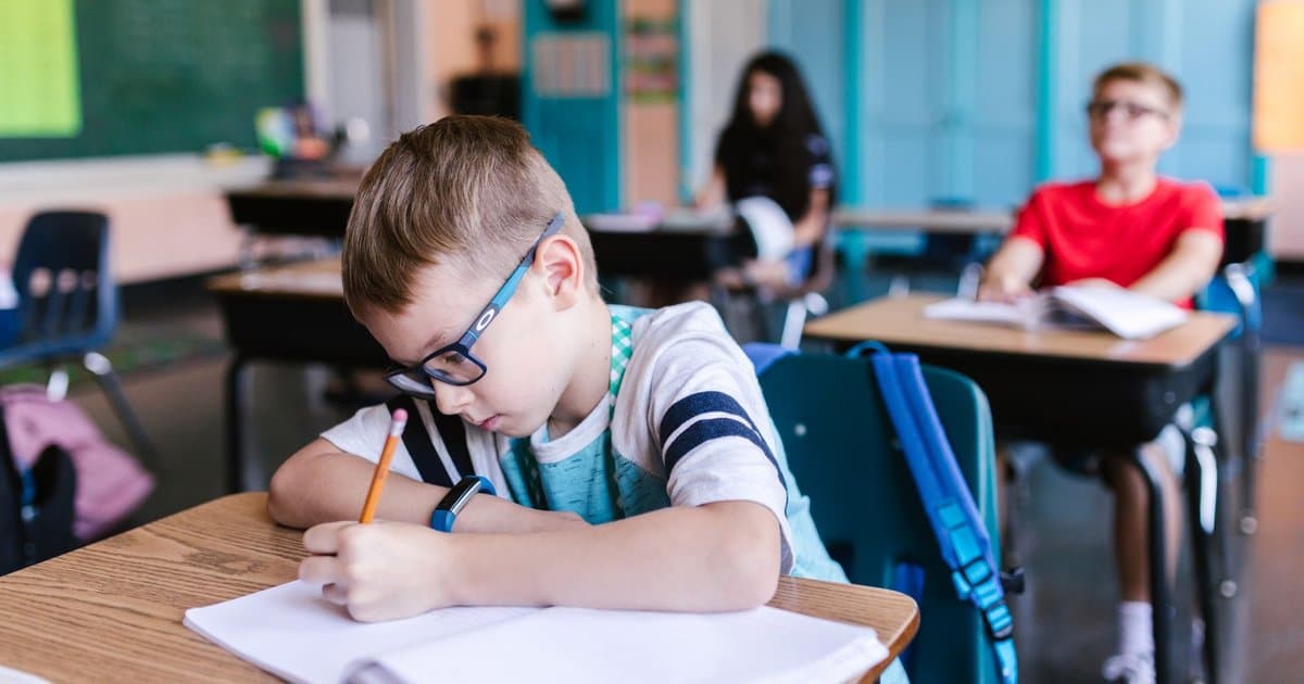 Elementary students writing at their desks in a classroom, illustrating narrative writing instruction methods.