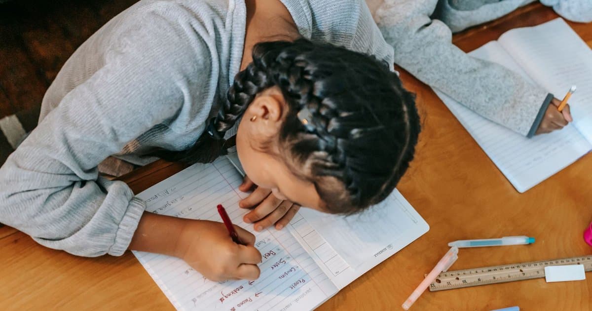 Children writing in notebooks at a wooden table, illustrating creative writing activities for kids.
