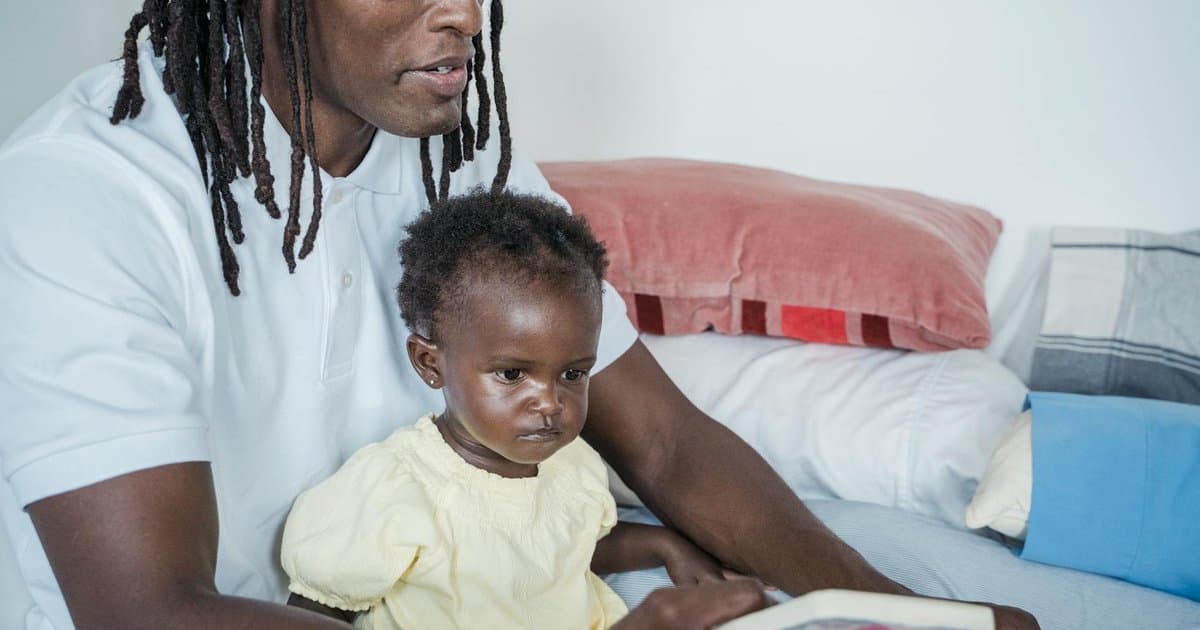A father and baby read a book together indoors, illustrating the bonding benefits of personalized children's books.